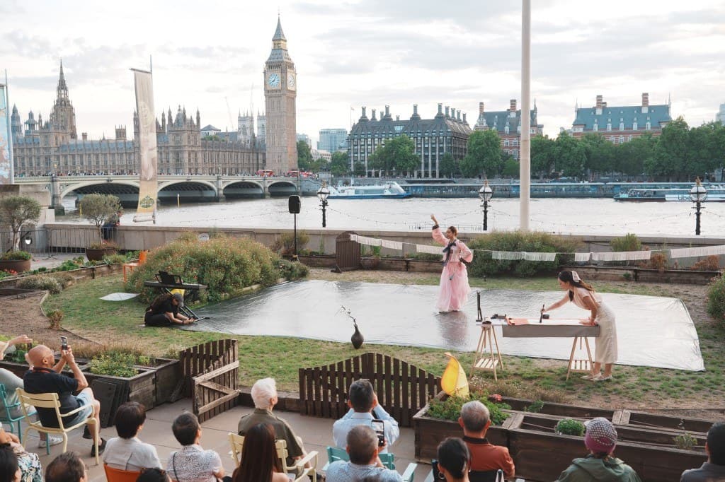 Outdoor performance on the South Bank with County Hall and Big Ben beyond the Thames