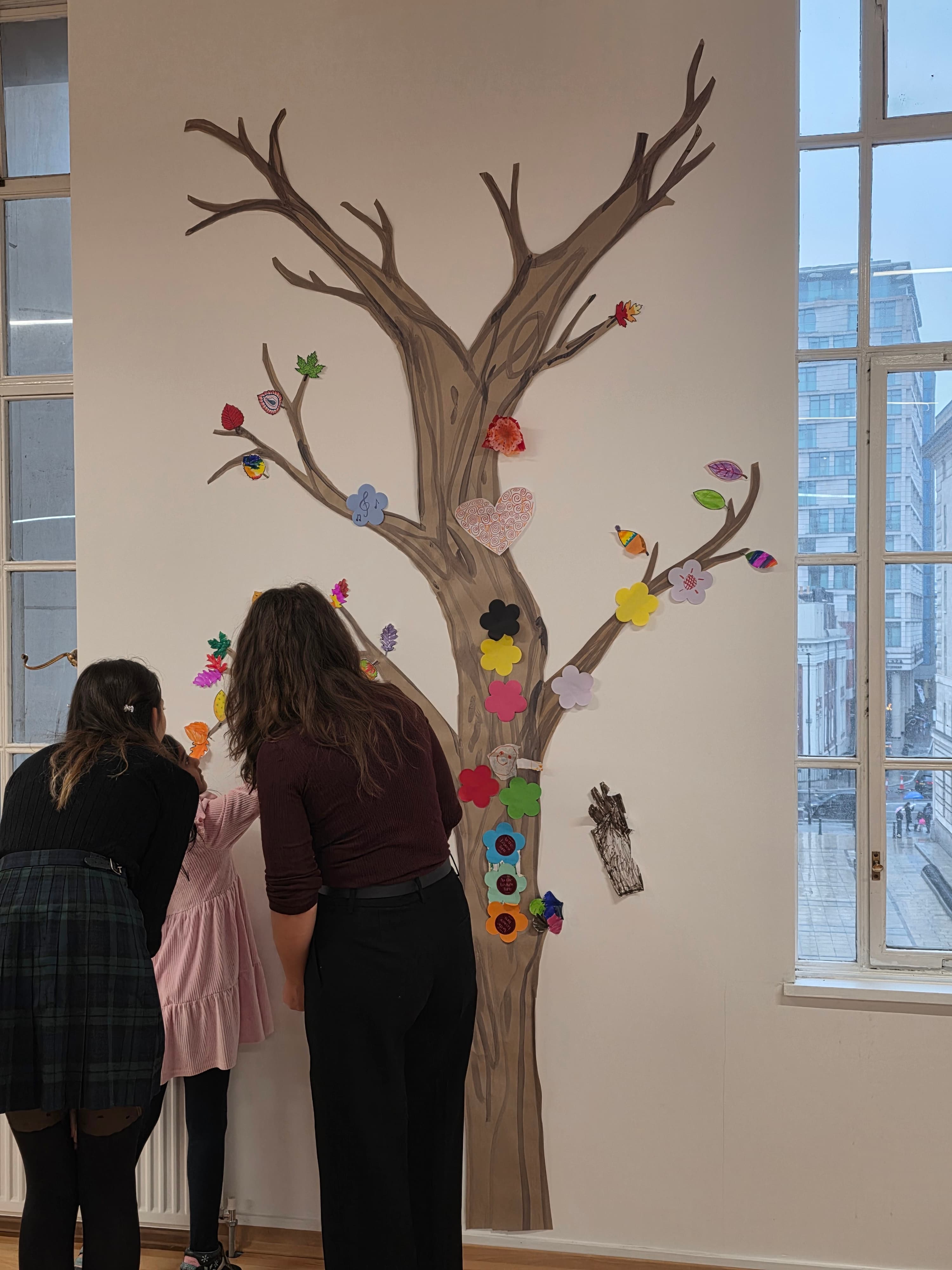 Visitors adding paper leaves to a tree mural at the Four Seasons Festival