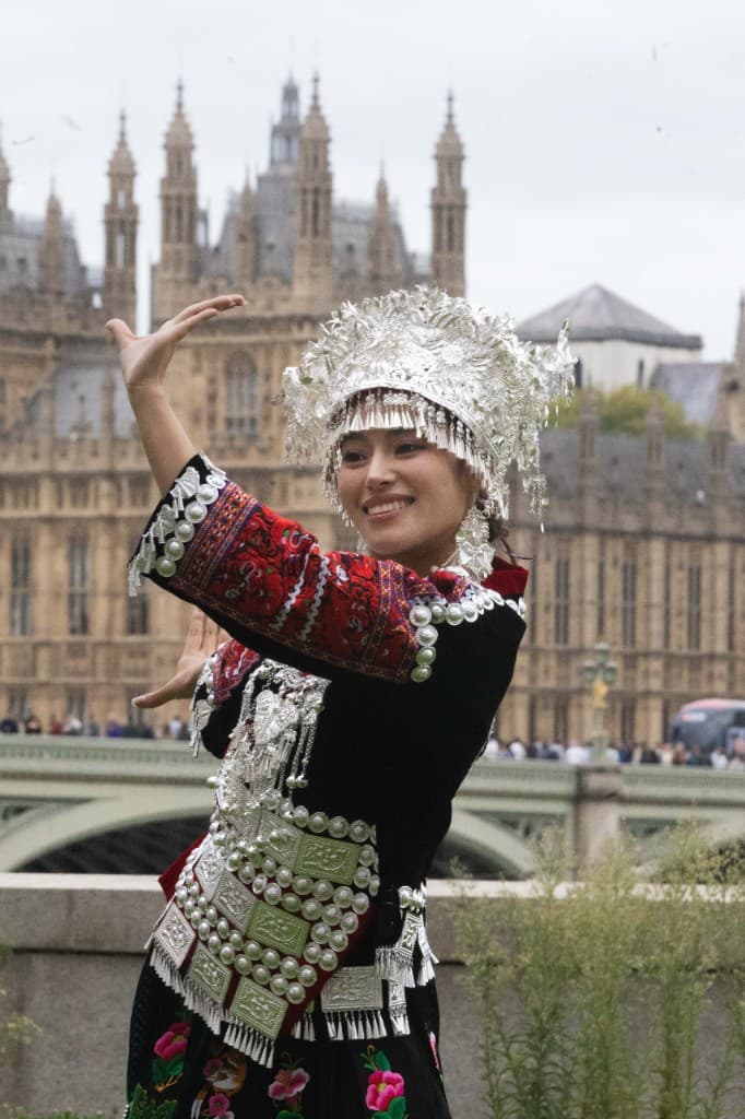 Miao ethnic dance performance in silver ceremonial dress with Big Ben behind